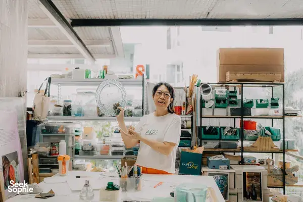 Tan Sock Fong holding a translucent glass centrepiece in the Art Glass Centre studio, Singapore—workshops in Singapore