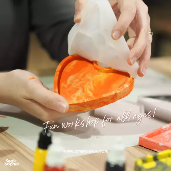 Clear container pouring orange resin onto a hexagonal coaster base during a marble & terrazzo coaster making workshops in Singapore