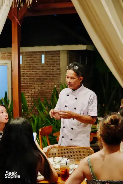 Chef Michael instructing guests during a Traditional Manggarai vegan cooking class, speaking in Labuan Bajo