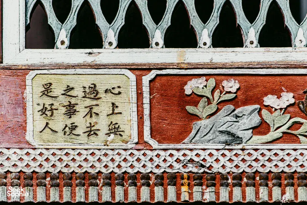 Close-up pintu masuk halaman rumah kaum Bai dengan panel ukiran hiasan dan kaligrafi Cina di pekan lama Xizhou, Dali