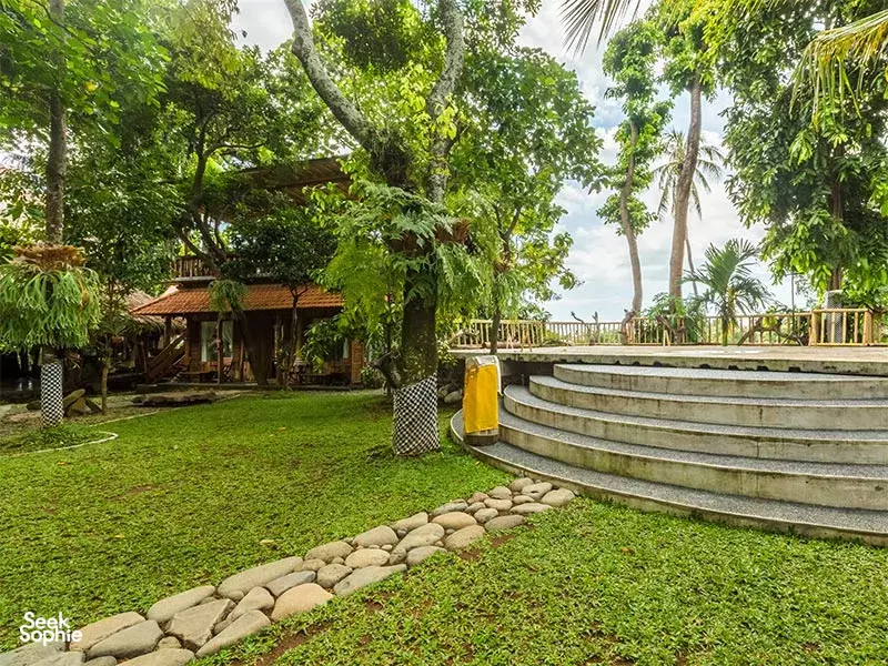 Terraced garden steps and grass lawn framed by tropical trees at Omunity Bali retreat in Bali for quiet meditation