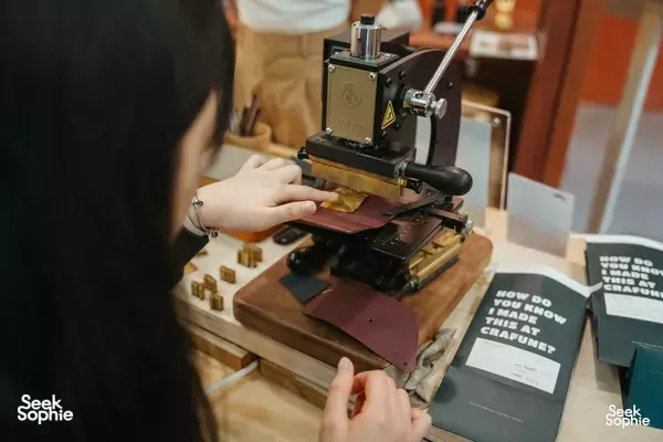 Crafune leathercraft in Singapore: hands use a manual press to cut and shape leather for a small item — workshops in Singapore