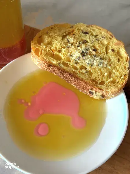 Sliced golden bread alongside yellow dip or soup on a plate, with a glass beside it in Singapore hidden gems