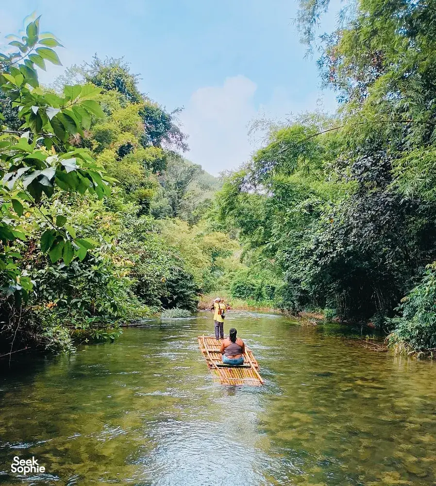 Raft on a calm river with passengers paddling through lush forest in Khao Lak, an adventure rafting moment