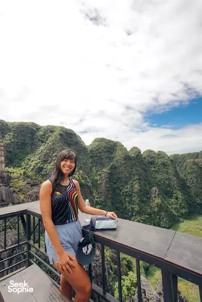 Traveller smiling at a viewpoint balcony overlooking limestone karst in Ninh Binh on a private day tour