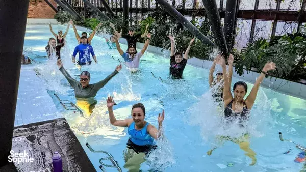 Aquaspin™ aqua fitness class with participants splashing and reaching arms up in a pool, Singapore — led by The Ripple Club