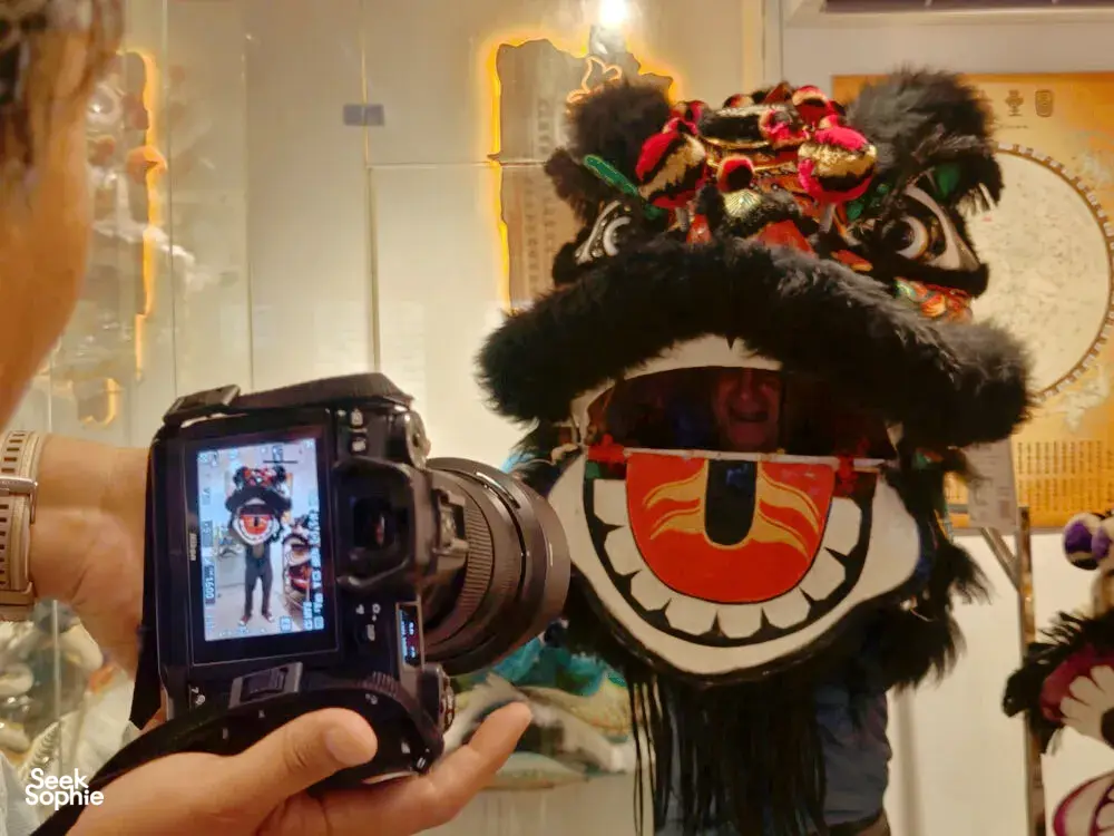 Close-up filming moment in a Ho Chi Minh City kung fu and lion dance workshop, with a lion head puppet filling the frame
