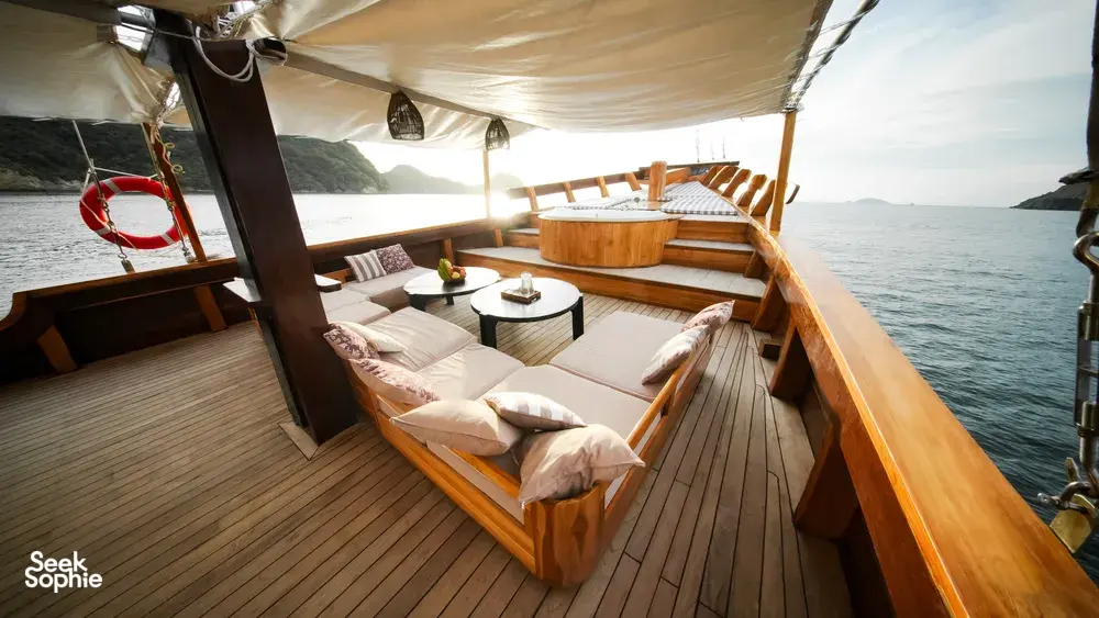 Angelica Liveaboard outdoor deck with cushioned sunbeds under a white canopy, cruising on a 3D2N luxe Komodo trip in Labuan Bajo