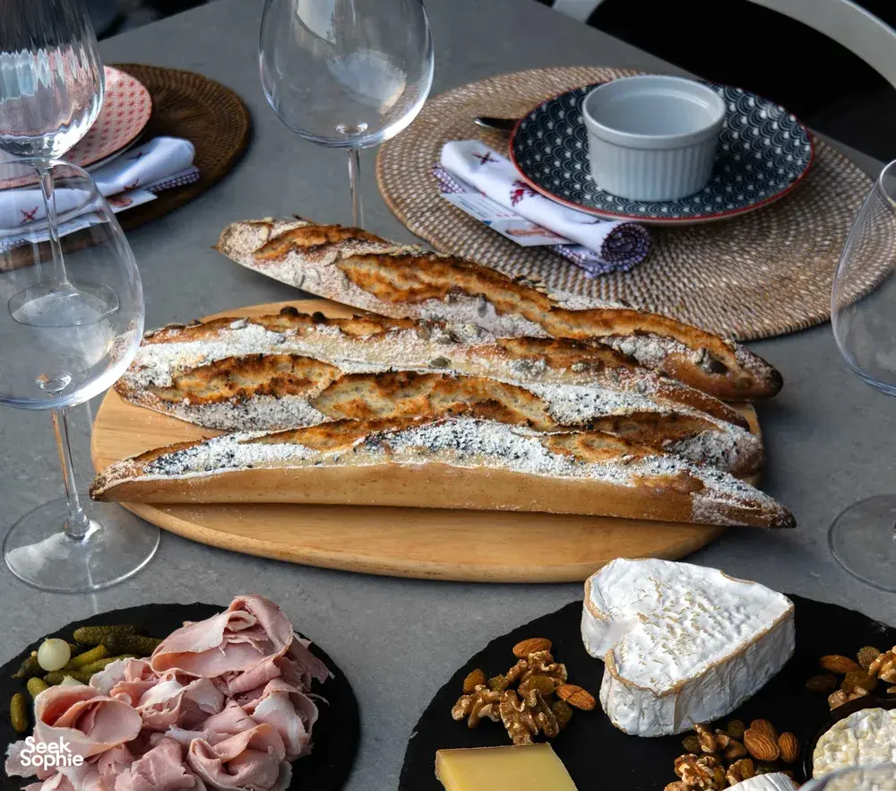 Baked baguettes with a French chef’s sunset charcuterie spread, wine glasses and cheese on a table for workshops in Singapore