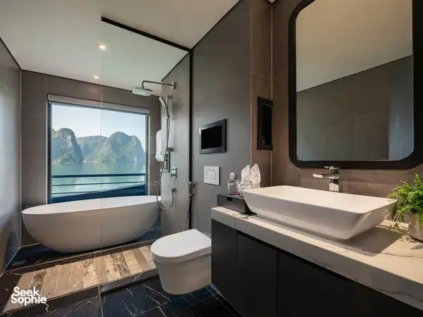 En-suite bathroom aboard Tulip Cruise with freestanding bathtub, modern vanity and rain-shower, facing a sea-view window in Halong Bay