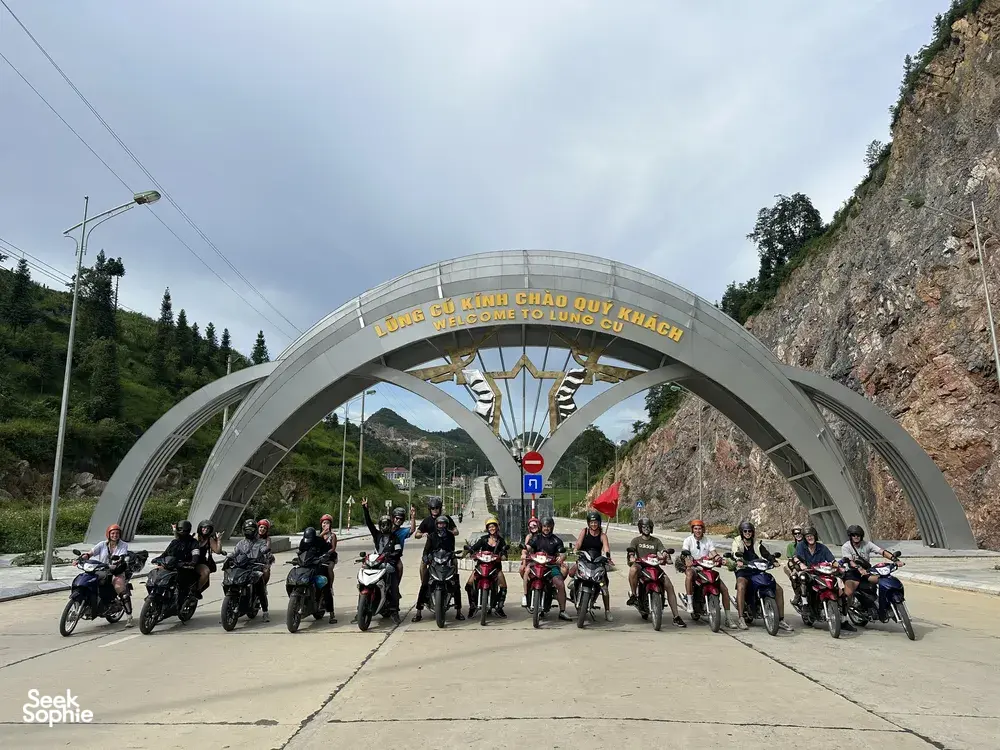 一群摩托车和骑手在河江一处山口入口整齐排开，准备开启河江环线之旅