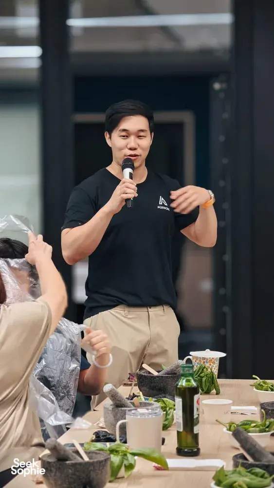 Instructor speaking to diners at a table with greens and bottles during pesto-making for teams in Singapore workshops in Singapore