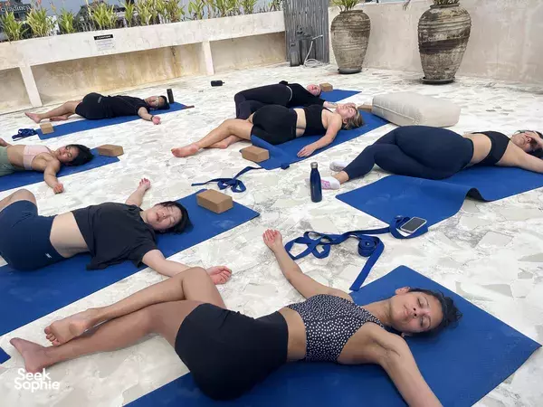 Supine yoga relaxation on blue mats with blocks during a private wellness session on a Bali terrace, Canggu