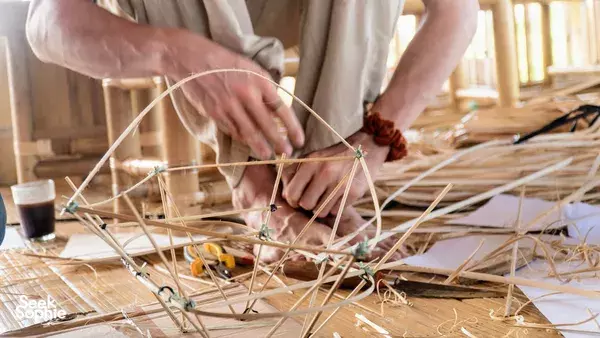 Craftsperson hands fastening bamboo members with tools on a workbench during a Bamboo Creative Bali build workshop in Bali