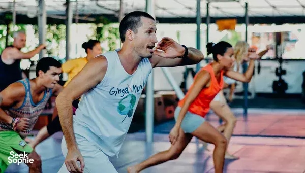 Instructor-led class at Phuket Cleanse in Phuket, a man in a tank top pauses mid-move while others stretch in rows