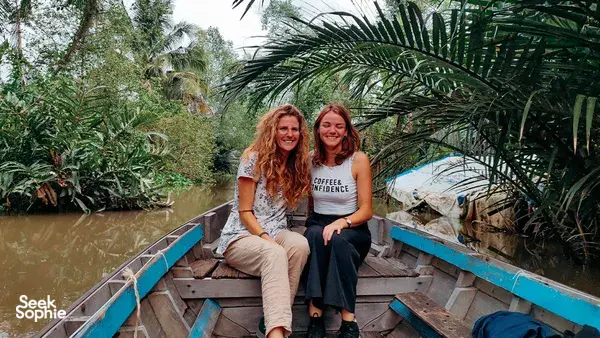 Travellers on a small wooden boat in the Mekong Delta, gliding past mangroves during a wildlife birdwatching ride