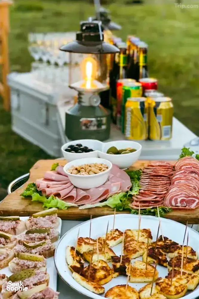 Outdoor picnic spread with charcuterie and grilled skewers on a wooden table during a Mission Liotard day trek in Shangri-La