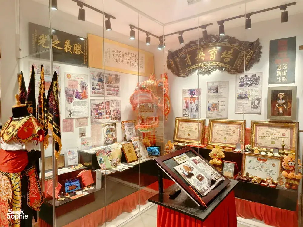 Museum showroom with glass cabinets, framed certificates and a lion-and-dragon display stand in Ho Chi Minh City kung fu exhibition