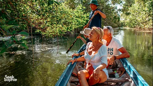 Local guide and travellers on a blue wooden boat on a calm river in the Mekong Delta, heading out for wildlife watching