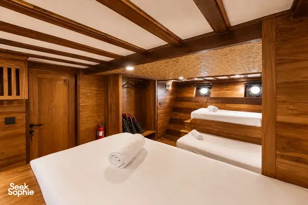 Travass Life phinisi cabin with two berths, rolled towels and warm wood-panelled walls, for a rare 3D2N shared trip on Komodo Island