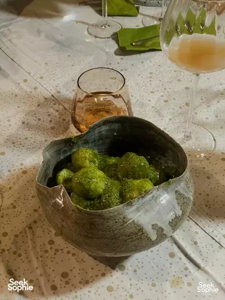 Ceramic bowl of green herb balls and drinks on a private dinner table, arranged for an Italian feast at a villa in Singapore private dining Singapore