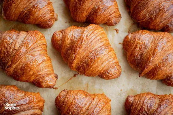 Croissant keemasan di atas kertas pembakar, baru dikeluarkan dari ketuhar, dalam pengalaman croissant dan kopi French Cooking Lab di Singapura