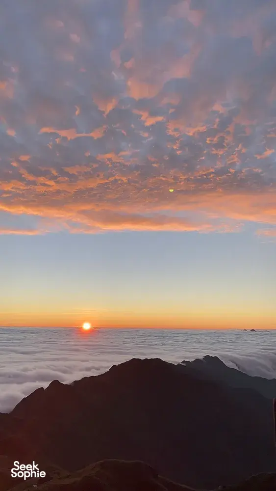 Rising sun breaking through colourful clouds over a sea of mist from Sapa during a 1-day eco trek, at Mt Fansipan