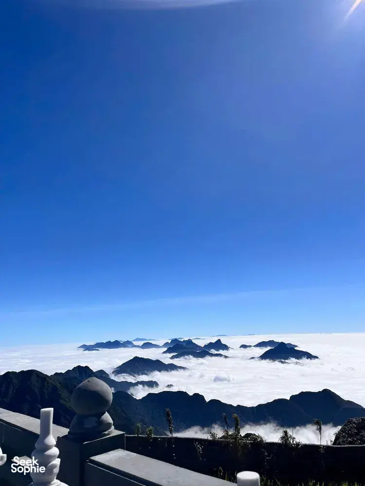 Balcony railing with white ornaments overlooking distant ridges and a sea of clouds at dawn during a 1-day eco trek, at Mt Fansipan