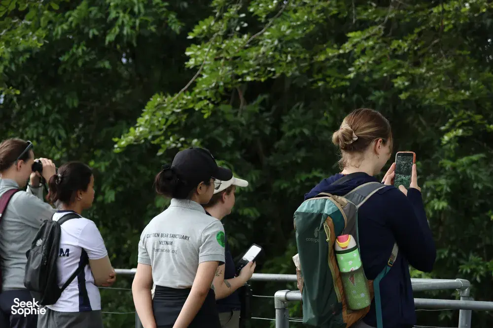 Small group on a forest walkway photographing wildlife with cameras and binoculars during an ethical nature tour in Cat Tien