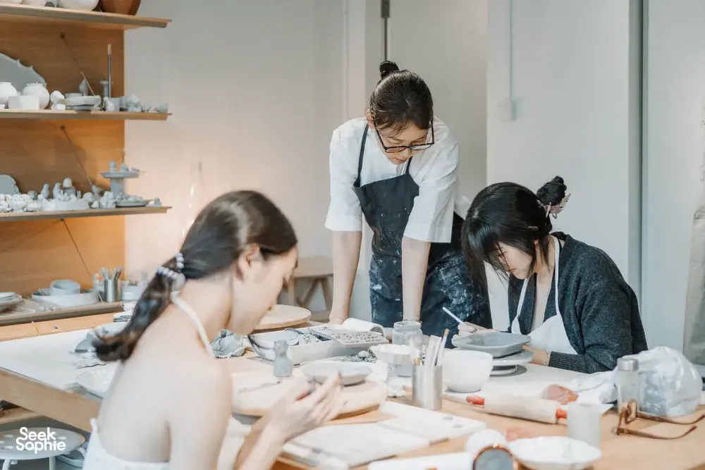 Ceramics workshop with an instructor in an apron guiding students as they handcraft tableware at a studio, workshops in Singapore