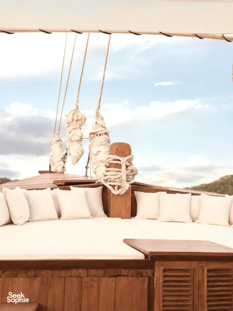 Komodo Island phinisi deck lounge with cushioned seating and hanging life jackets, part of a Travass Life 3D2N shared trip