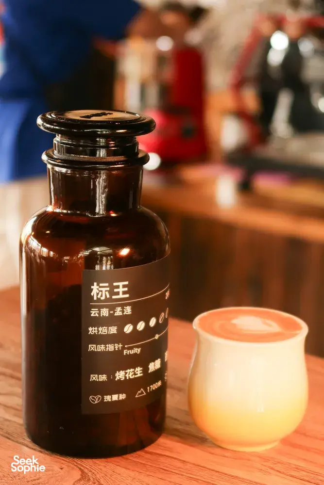 Yunnan coffee tasting props at Seeker Yunnan Coffee Estate in Lijiang: labelled grinder jar beside a creamy drink cup