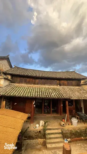 Courtyard of traditional houses in a Shangri-La pottery village, with stone steps, clay pots and a cloudy sky overhead