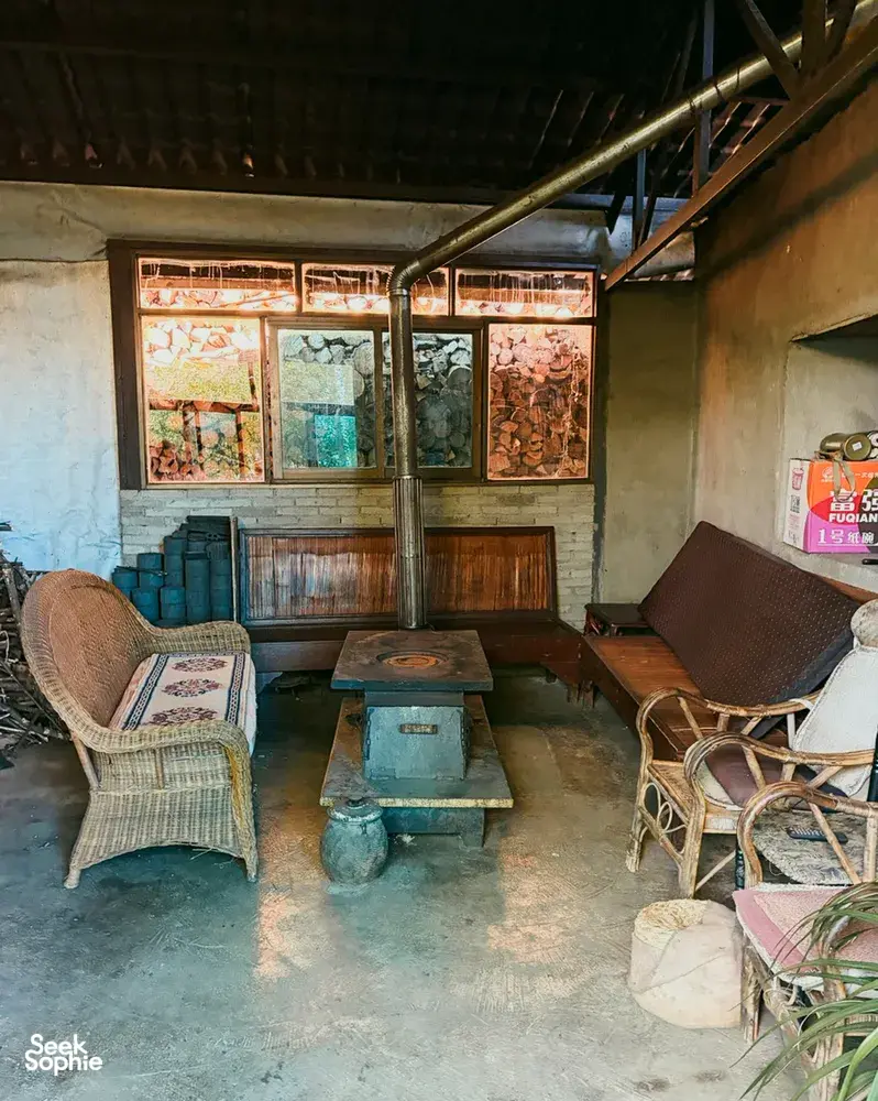 Guesthouse lounge in Lijiang with woven chairs, wooden tables, and a service counter by large windows, included in the stay