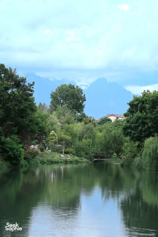 Calm courtyard pond reflecting trees and distant mountains from The Bivou Lijiang in Shuhe Ancient Town, Lijiang