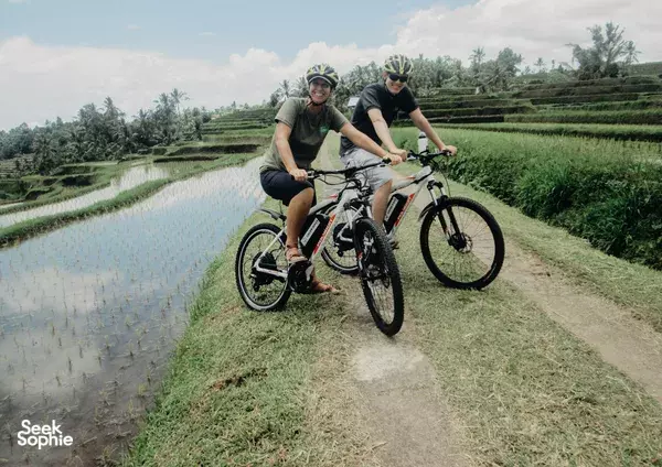 Electric bikes on the Jatiluwih UNESCO rice-terrace path in Bali, with Green Bikes Bali riders pedalling past irrigation pools
