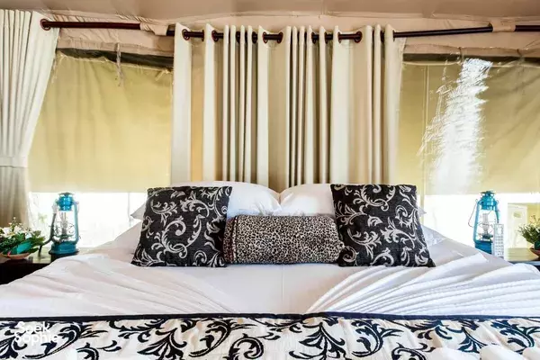 Leopard Trails luxury bed inside a Wilpattu safari tent, dressed with cushions and drawn curtains for a restful stay