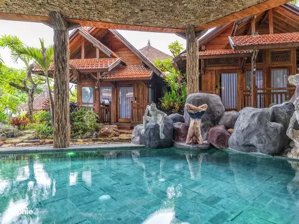 Tropical courtyard pool surrounded by large stones and wooden villas at Udara Yoga Detox & Spa in Bali