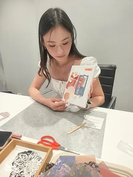 A participant places pieces on her vision board for gemstones in Singapore, with templates and tools on the table; workshops in Singapore