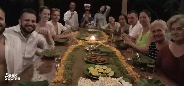 Retreat group sharing dinner around a long table with candles and plates under a shaded pavilion at Omunity Bali, Bali