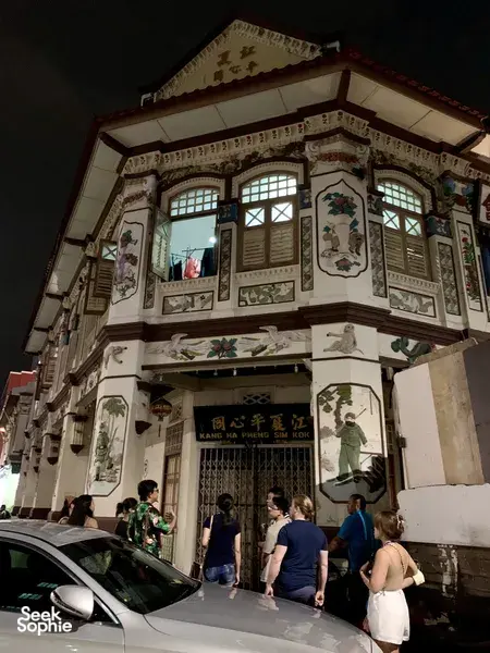 Ornate heritage shophouse facade with visitors outside on Indie Singapore Tours’ private night walk through Geylang, Singapore hidden gems