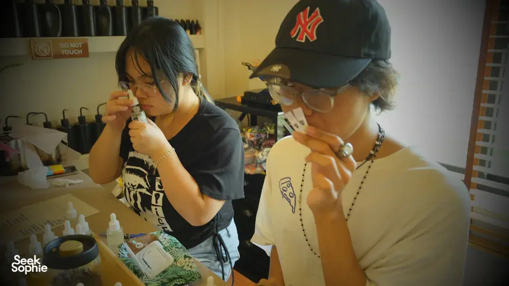 Two people leaning over scent bottles and samples, blending fragrance notes at Perfume Play in Singapore during workshops in Singapore