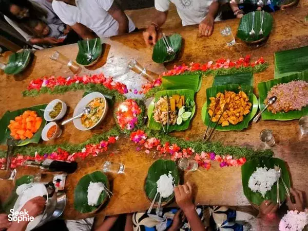 Hands preparing ritual plates with green leaves and flower petals on a wooden table during cleansing at Omunity Bali, Bali