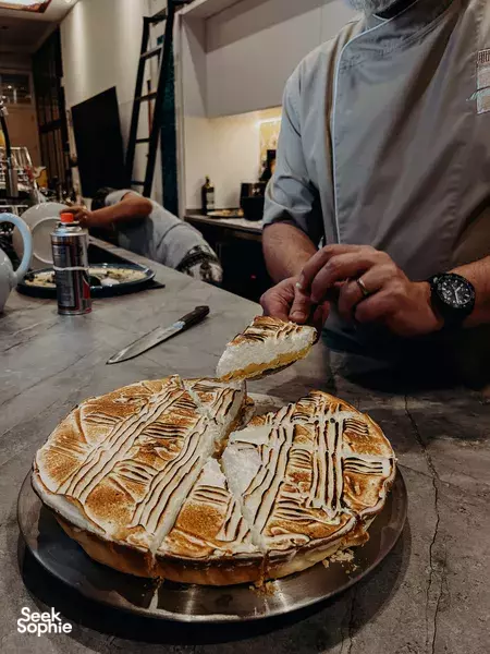 Chef prepares a patterned baked pastry on a metal tray, working at the stone counter in a Peranakan shophouse for private dining Singapore