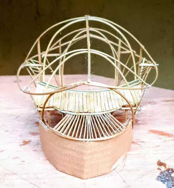Close-up of a small woven bamboo dome and railing model on the floor inside a Bali workshop space for building prototypes
