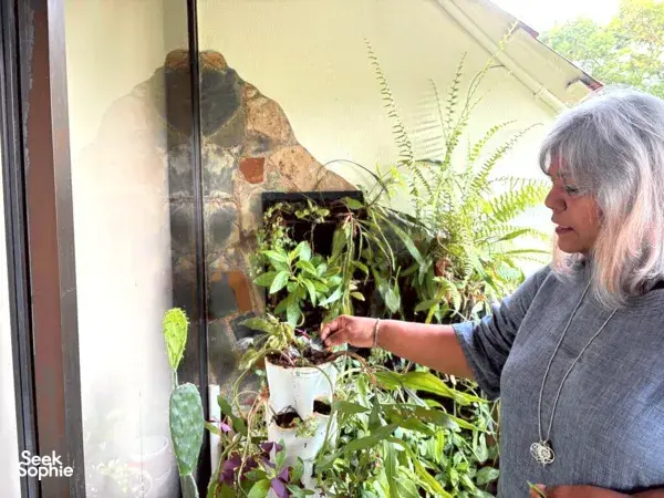 Participant tending a small balcony herb display, placing edible plants in pots for a bread-and-dips workshop in Singapore