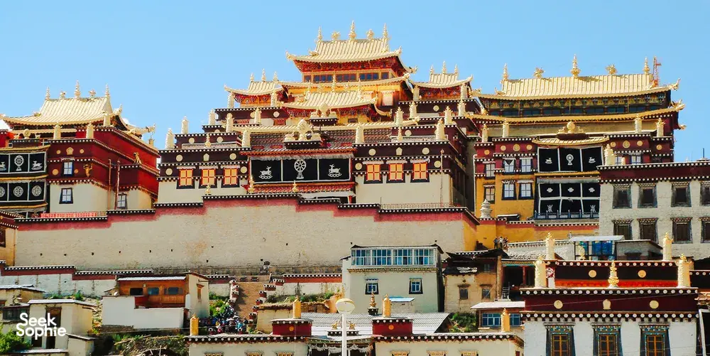 Traditional Tibetan monastery with ornate multi-storey pagoda roofs against blue sky in Shangri-La during daytime