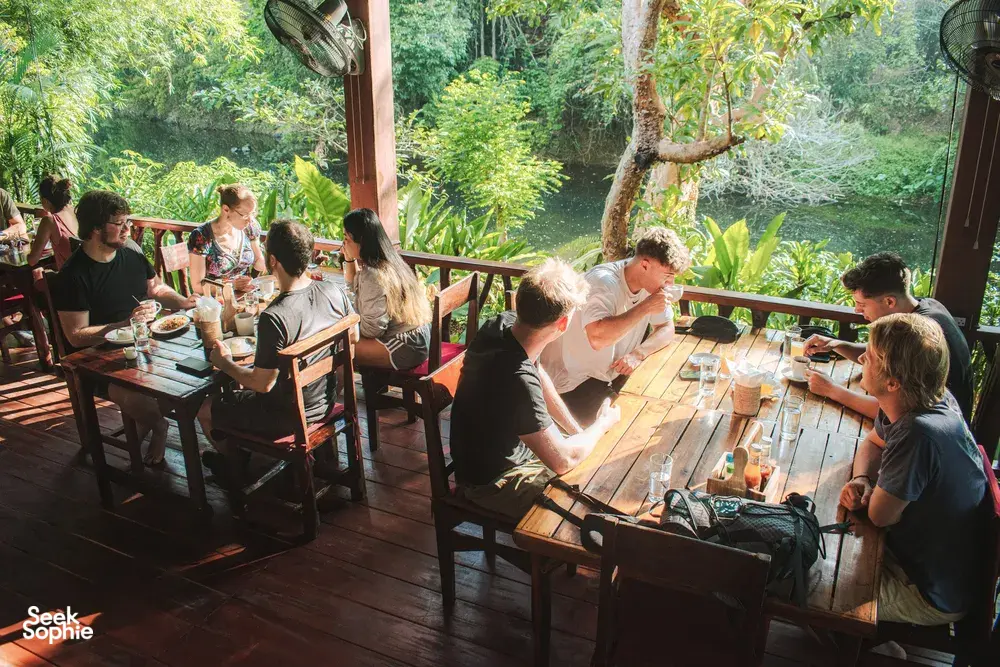 Guests eating together at a riverside dining deck at Khao Sok Riverside Cottages in Khao Sok National Park