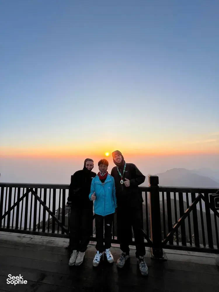 Travellers posing on a balcony at sunset above Sapa after a guide-led 1-day eco trek viewpoint, Mt Fansipan