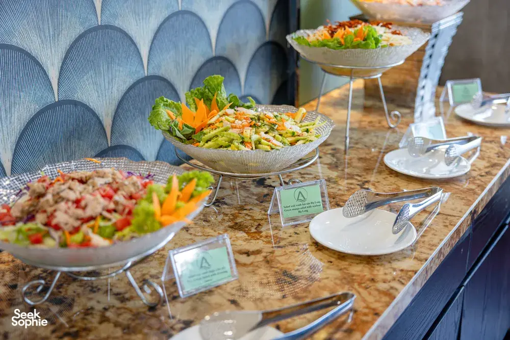 Halong Bay party cruise buffet table with salad bowls and serving utensils along a stone counter top, ready for guests to eat
